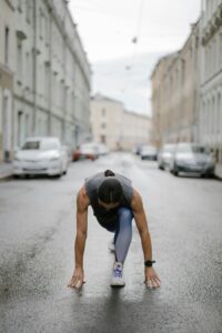 Woman in fitness attire getting ready to run on a city street. Emphasizes urban fitness and motivation.