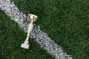 A gold trophy placed on green grass beside a white field line.